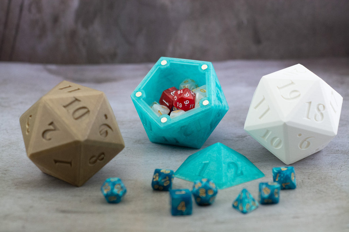 Tan, teal and white D20 dice vaults, the teal one open with dice inside