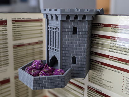 Gray castle dice tower clipped to the top of a DM screen, with purple dice in its tray